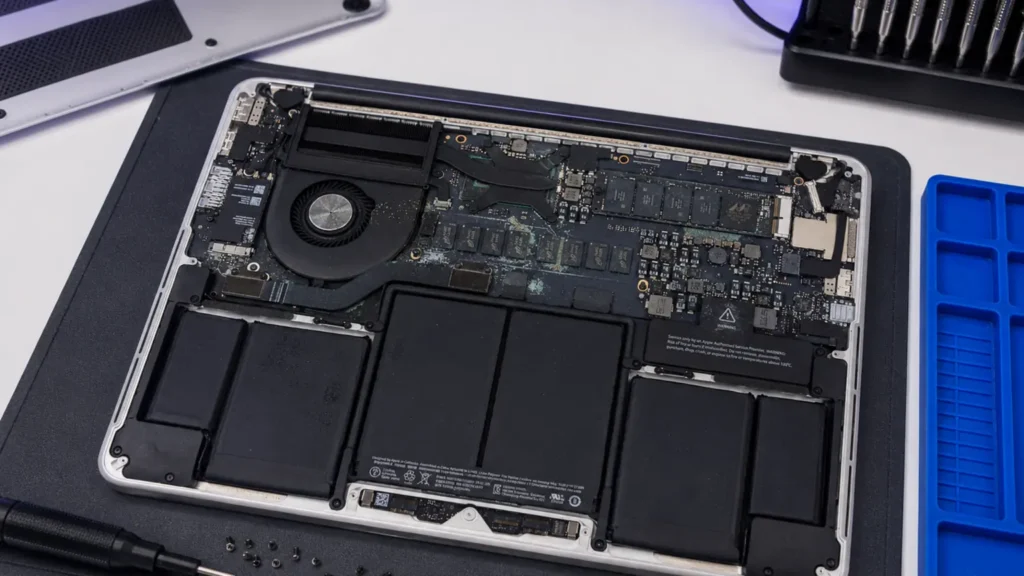 Opened liquid-damaged laptop showing corrosion across the logic board.