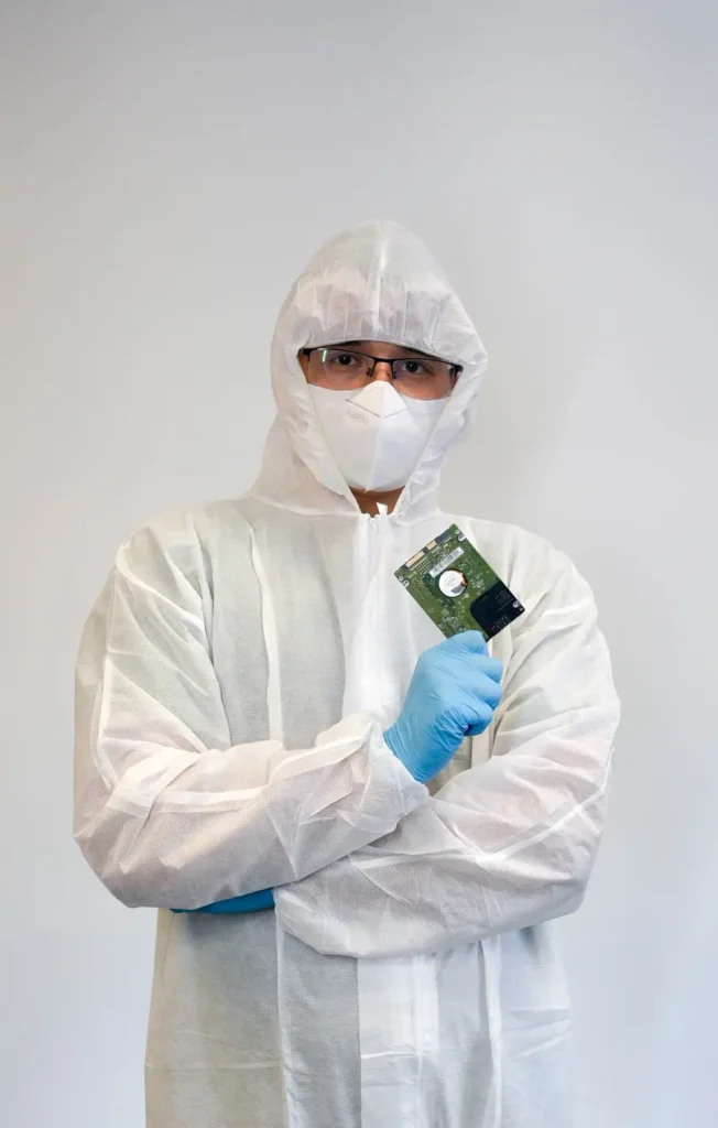 A WeFixed data recovery specialist in a cleanroom suit holding a hard drive board in Arlington, VA